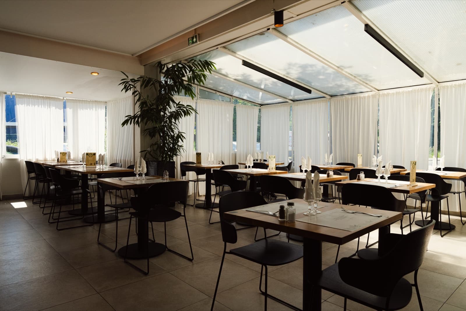 La salle du restaurant Le Sénia, verrière et tables dressées