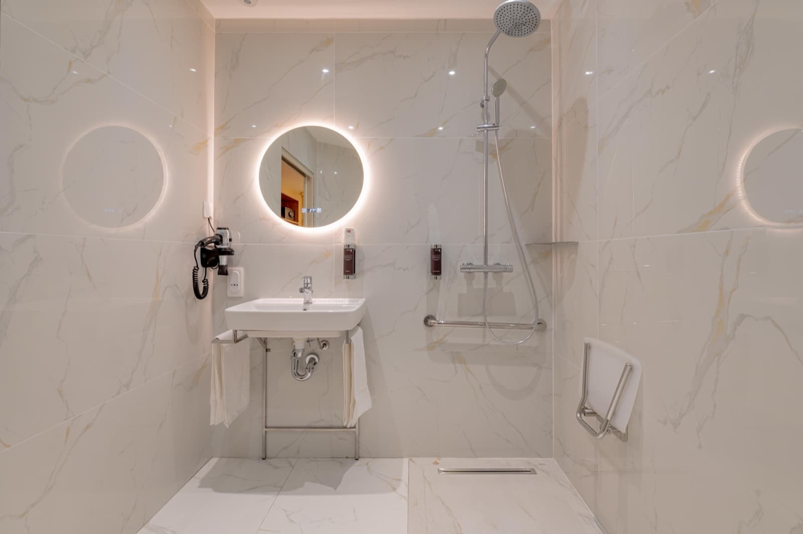 Salle de bain en marbre blanc, vasque et miroir rond rétroéclairé