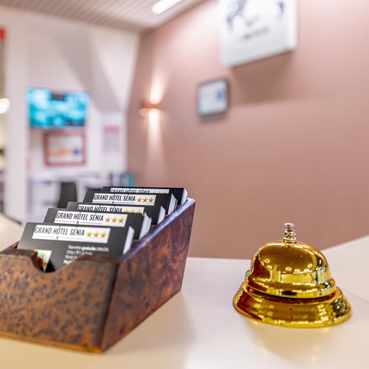 Cloche dorée et brochures Grand Hôtel Sénia sur le comptoir de la réception
